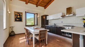 A modern kitchen with wooden flooring, a dining area with a table and chairs, and a view of the outdoors. - Villa in Piandimeleto With Pool & Sauna (Piandimeleto)