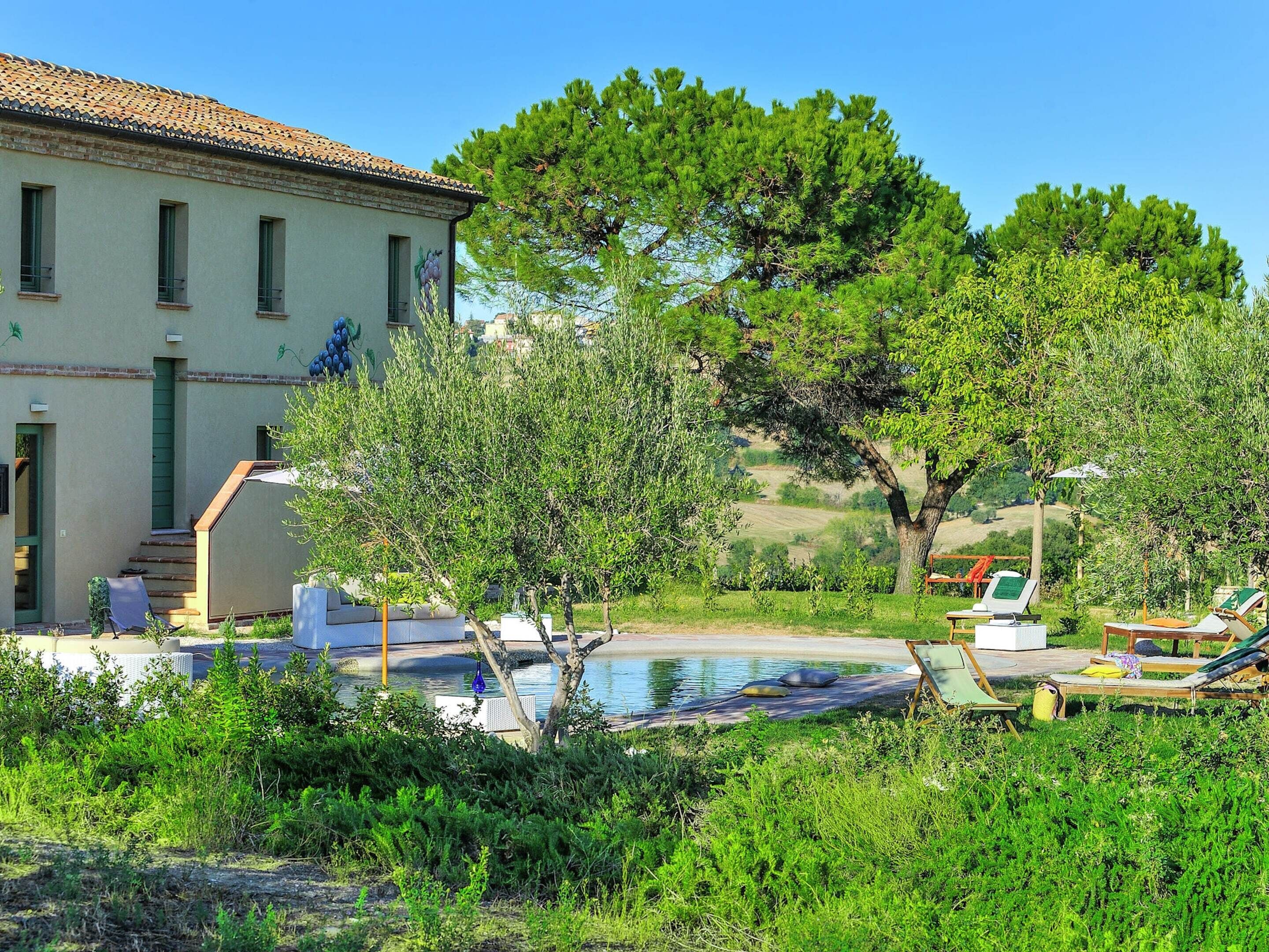 Una villa con piscina, mobiliario de exterior y jardín.