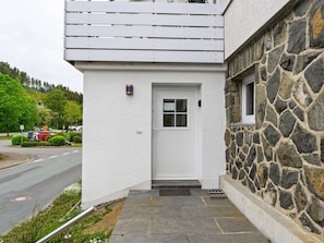 Stunning building with a white exterior and stone facade, featuring a welcoming entrance with a white door and small window.