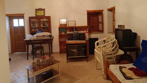 A living room with a wooden ceiling, a television, a bookshelf, a desk with a computer, and a bed with a blanket. - Hillview Holiday Home in Kalavrouza (Nafpaktos)