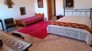 A bedroom with two beds, a wooden chair, a table, and a red rug. - Hillview Holiday Home in Kalavrouza (Nafpaktos)