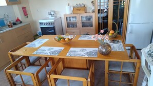 A dining area with a wooden table, chairs, and a vase with flowers. - Hillview Holiday Home in Kalavrouza (Nafpaktos)