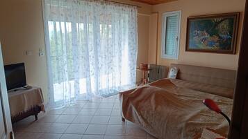 Un dormitorio con cama, televisor sobre una mesita auxiliar, radiador y un cuadro en la pared.