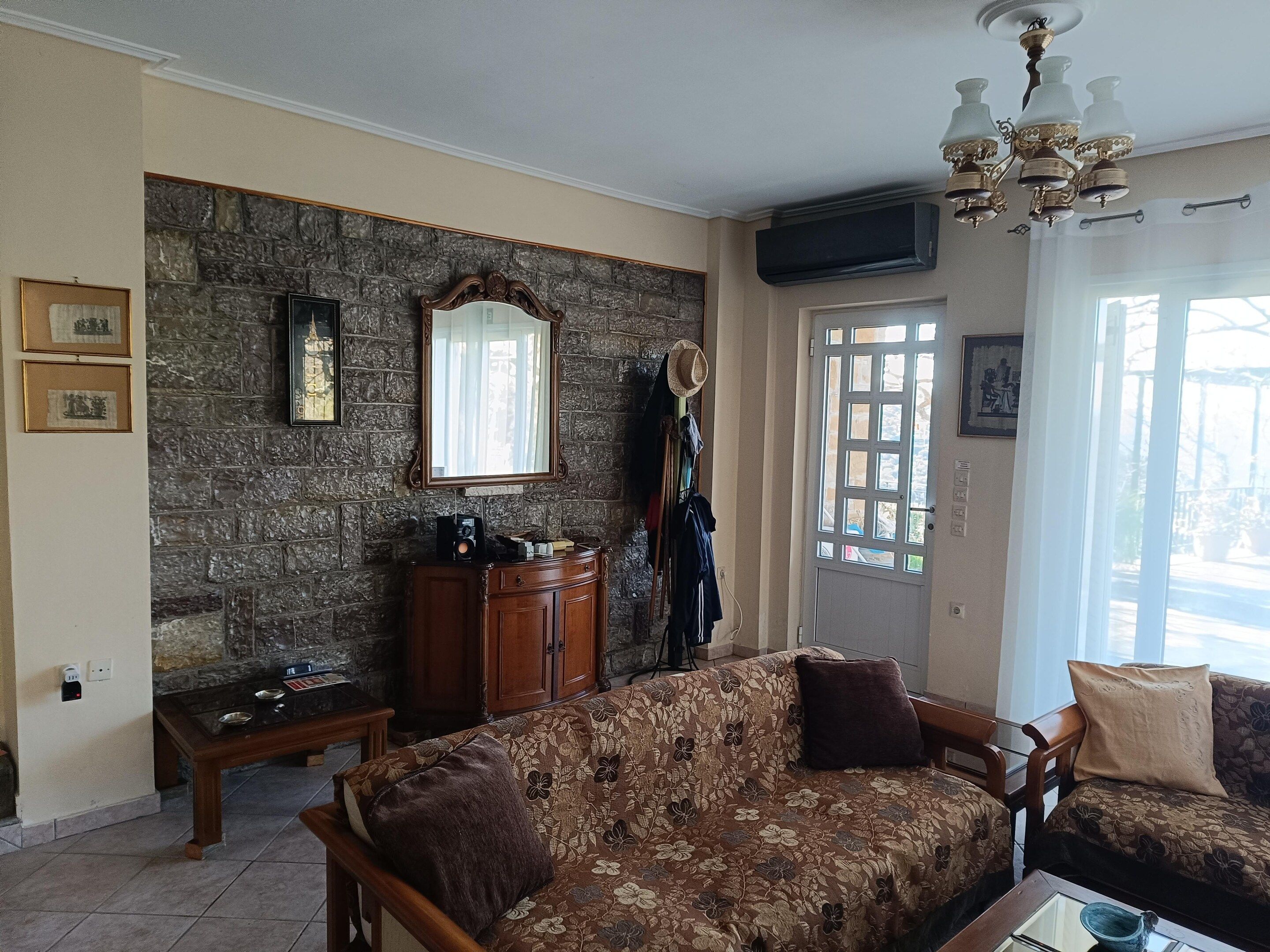 Un salon avec un mur en pierre, un meuble en bois, un canapé et une porte dotée d’une fenêtre.