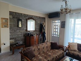 Una sala de estar con pared de piedra, un mueble de madera, un sofá y una puerta con ventana.