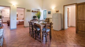 Una cocina amplia con una mesa, sillas y un refrigerador. Hay armarios y una ventana con vistas.