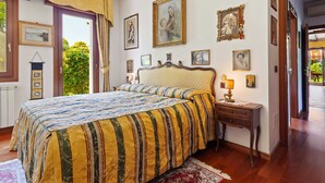 A bedroom with a large bed, a nightstand with a lamp, and several framed pictures on the wall. - Belvilla by OYO Villa Pratolina Agli Alberoni (Venice)