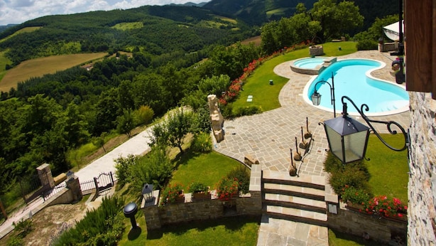 Ein Pool mit einer Steindeck, umgeben von einer Steinmauer und einem Blumengarten.