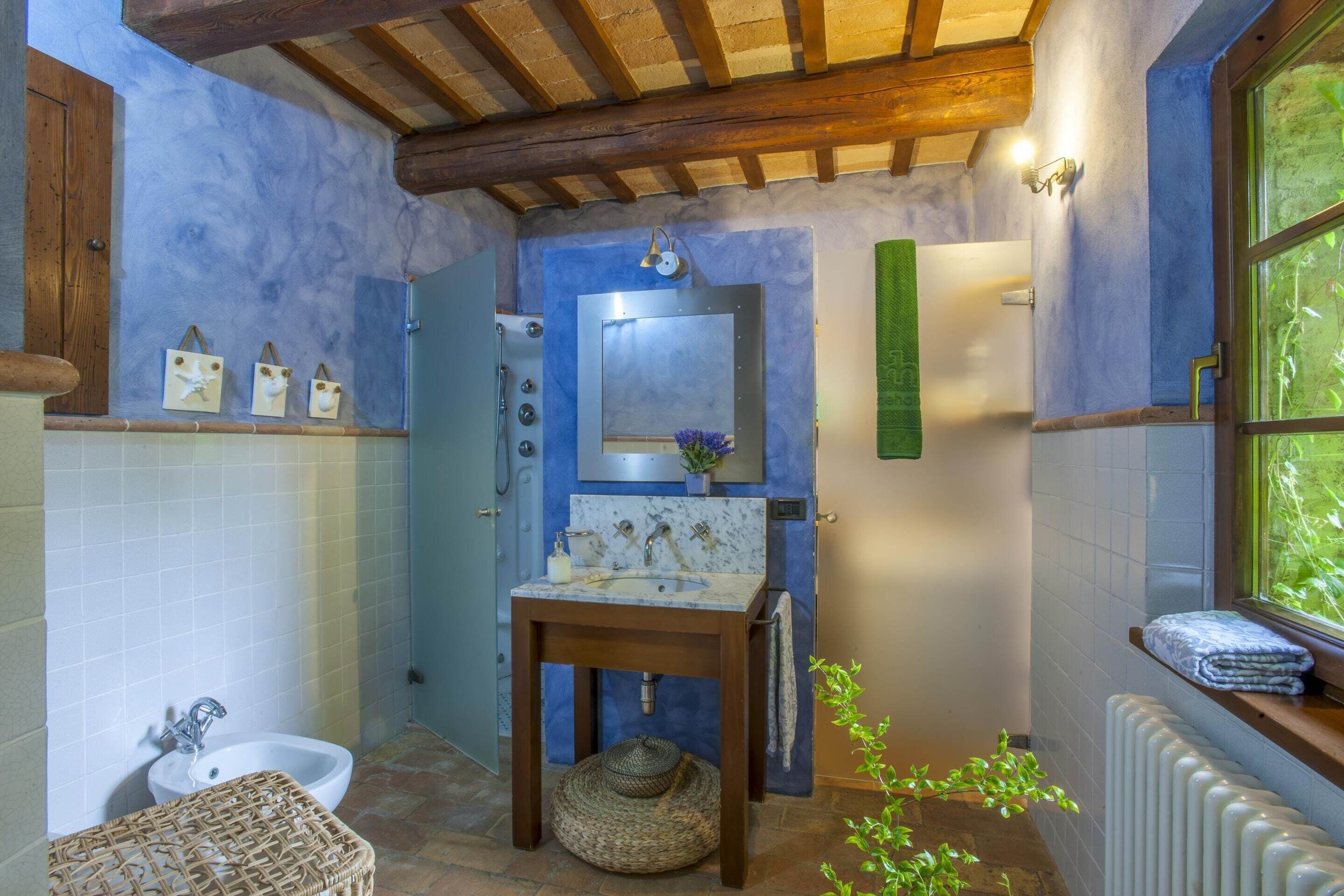Une salle de bain avec un banc en bois, un lavabo, un miroir et un porte-serviettes.