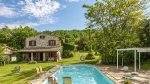 A stone house with a swimming pool, surrounded by a well-maintained lawn and trees. - Marche Villa Close Culture (Fermignano)