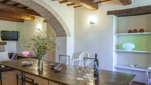 A rustic dining area with a wooden table, chairs, and a vase of flowers. - Marche Villa Close Culture (Fermignano)