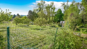 Un giardino recintato con diversi alberi e un piccolo edificio sullo sfondo.