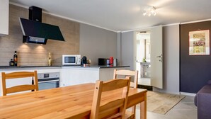 Una cucina moderna con un tavolo e sedie in legno, un forno a microonde e un forno integrato.