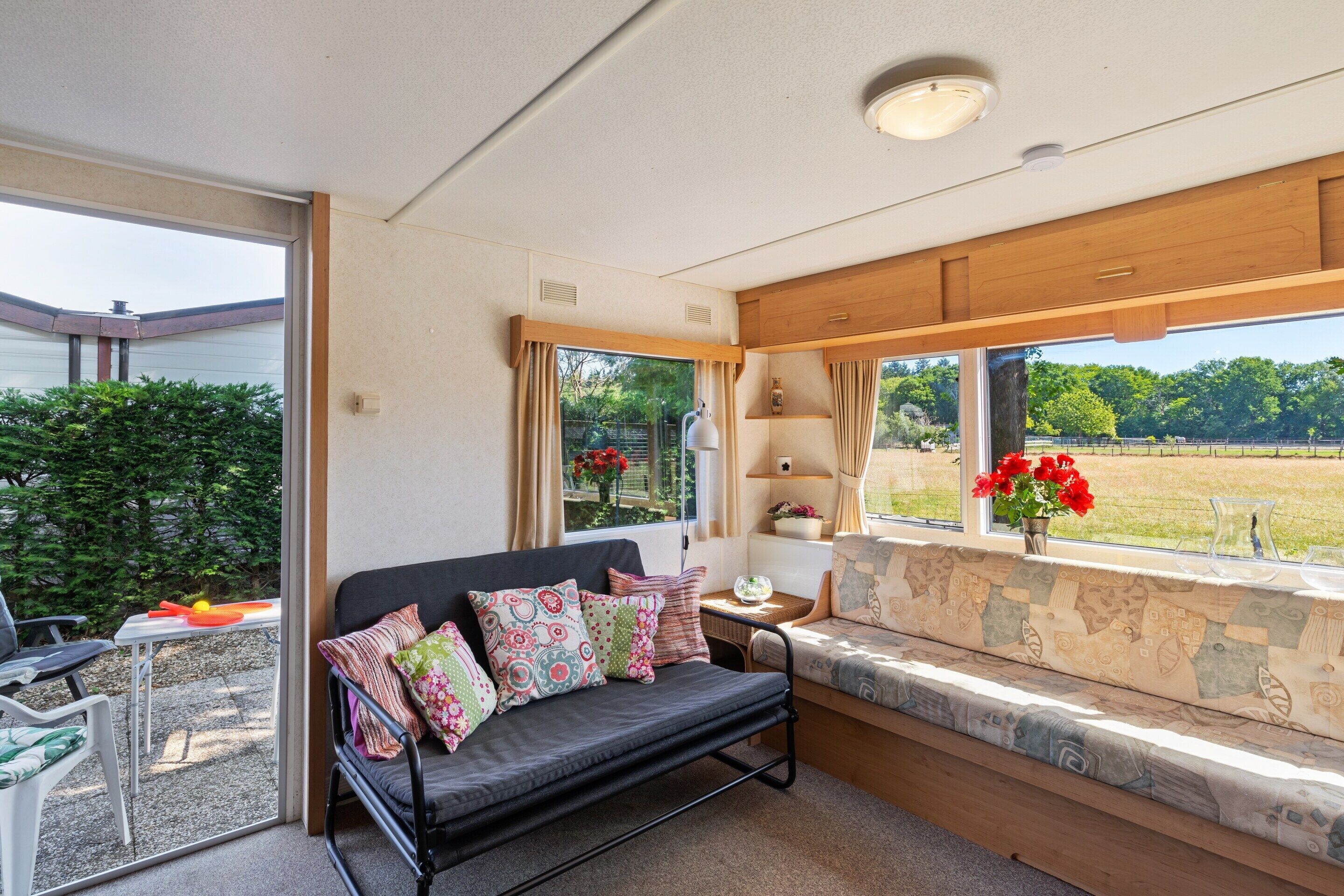 Ein gemütliches Zimmer mit einer Couch, einer Fensterbank und Blick auf einen Garten.