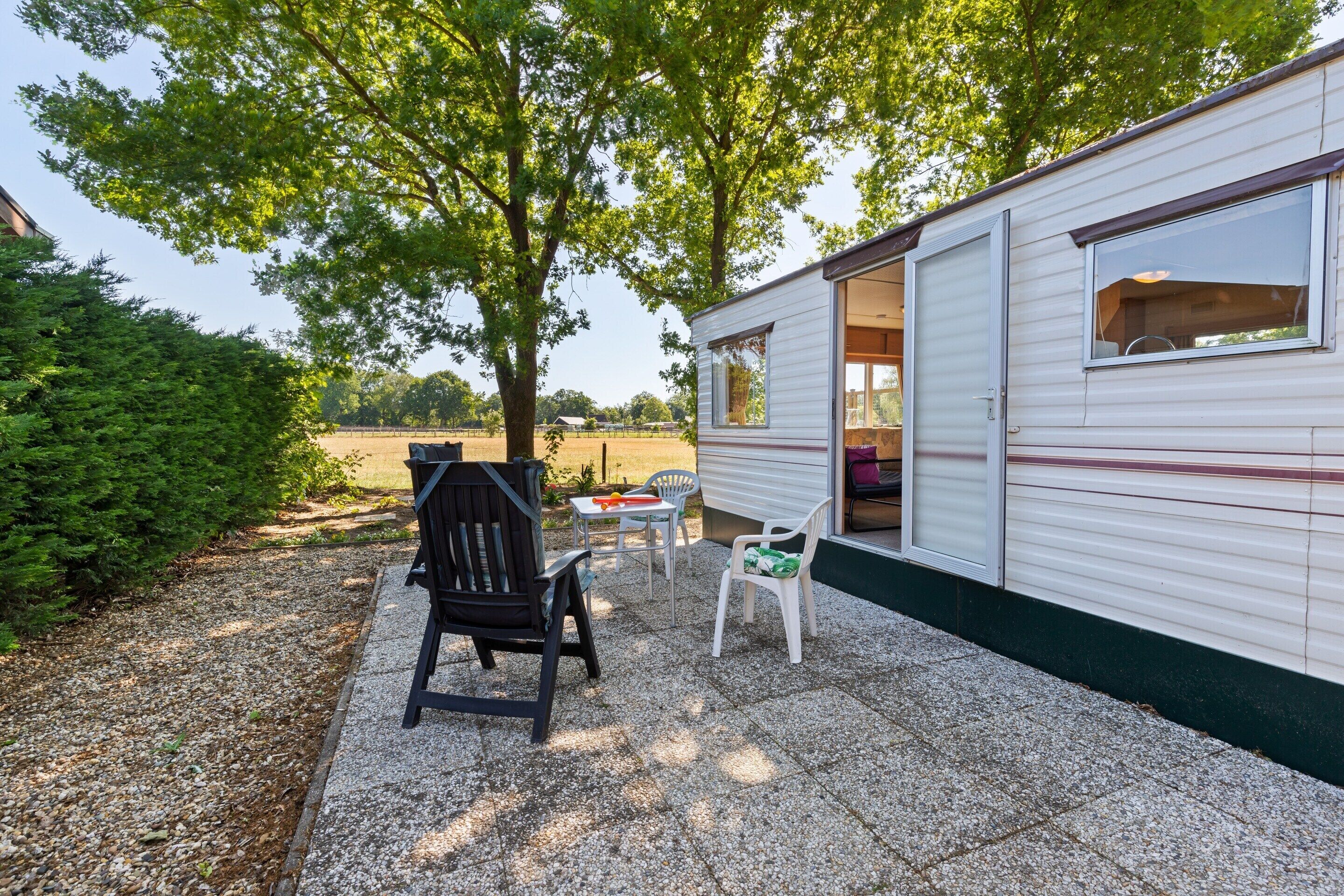 Una casa móvil con un patio que incluye una mesa, sillas y una parrilla.