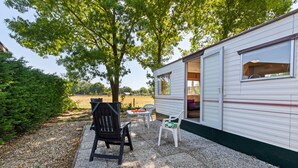 Une maison mobile dotée d’un patio comprenant une table, des chaises et un barbecue.
