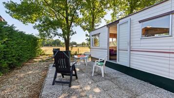 A mobile home with a patio area featuring a table, chairs, and a grill.