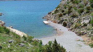 A rocky shoreline with clear blue water and a gravel path leading to a beach. - Comfortable Apartment in Novalja near Zrče Beach  (Novalja)