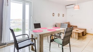 A modern dining area with a table, chairs, and a view through a large window. - Comfortable Apartment in Novalja near Zrče Beach  (Novalja)