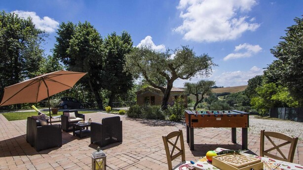 An outdoor patio with a foosball table, a table with board games, wicker furniture, and a lantern. - Holiday Home in Fano Near Adriatic Sea (Fano)