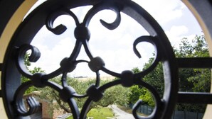 A circular metal gate with intricate designs, leading to a garden with a gravel path and greenery. - Holiday Home in Fano Near Adriatic Sea (Fano)