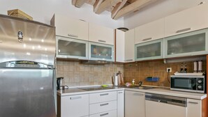 Cozinha moderna com eletrodomésticos de aço inoxidável, armários brancos e painel de azulejos.