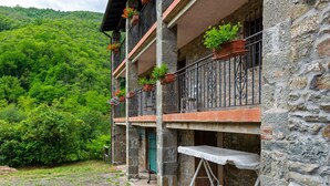 A stone building with balconies, potted plants, and a cobblestone courtyard. - Belvilla by OYO La Casa sul Fiume First Floor (Fosciandora)