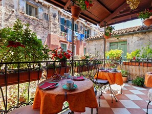A terrace with outdoor seating, potted plants, and a view of old buildings. - Belvilla by OYO Ca' Del Cinema (Venice)