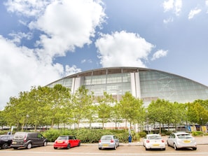 A modern building with a curved glass facade, surrounded by trees and parked cars. - Simplistic Apartment in Milton Keynes near Willen Lake (Milton Keynes)