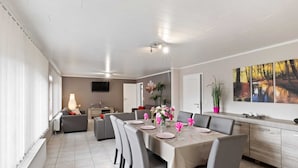 A modern dining area with a table set for four, a sofa, and a television in the background. - Cozy Apartment in Waimes near Ovifat & Robertville Lake (Waimes)