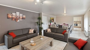 A modern living room with two sofas, a coffee table, and a dining area in the background. - Cozy Apartment in Waimes near Ovifat & Robertville Lake (Waimes)