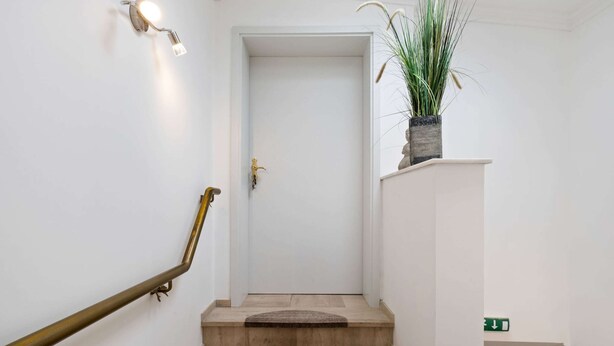 A staircase with a brass handrail, a potted plant on the landing, and a white door at the top. - Cozy Apartment in Waimes near Ovifat & Robertville Lake (Waimes)