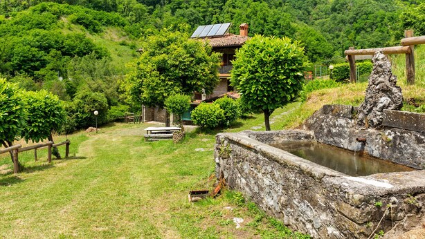 A traditional building with a sloped roof, surrounded by lush greenery and hills.