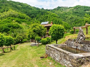 A traditional building with a sloped roof, surrounded by lush greenery and hills. - Belvilla by OYO La Casa sul Fiume 4 (Fosciandora)