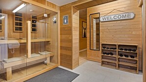 A wooden interior with a glass sauna, wooden benches, a welcome sign, and shoe storage. - Elegant Chalet in Manhay With Sauna (Manhay)