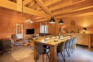 Un interior de madera con una gran mesa de comedor, sillas, chimenea y zona de cocina.
