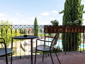 A balcony with a table and two chairs, overlooking a swimming pool and garden. - Peaceful Stay in Collazzone Hills (Collazzone)