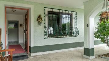 A clean, well-maintained entrance with a tiled floor, a red mat, and a wooden bench.