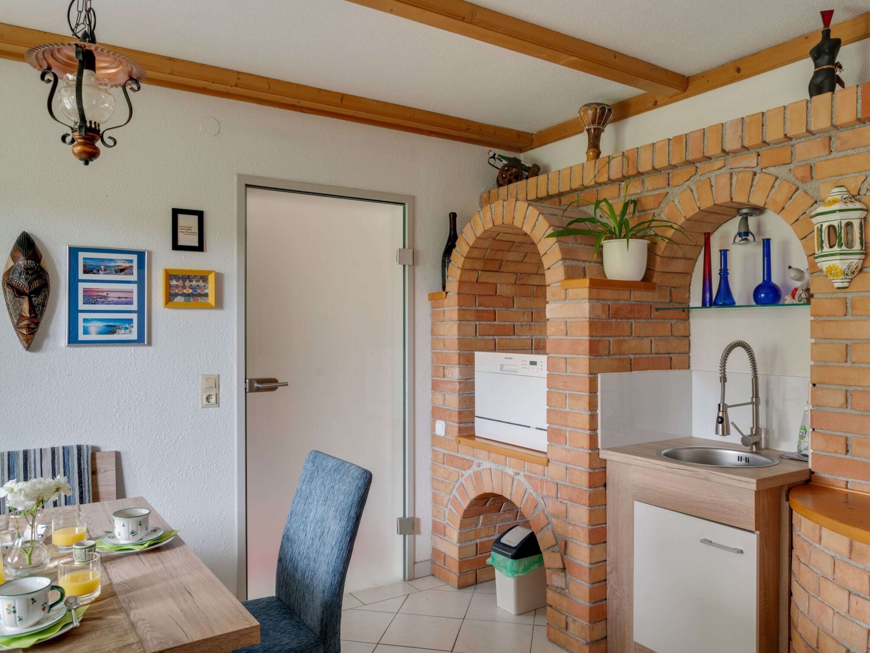Una cocina con arco de ladrillo, un fregadero y un refrigerador.