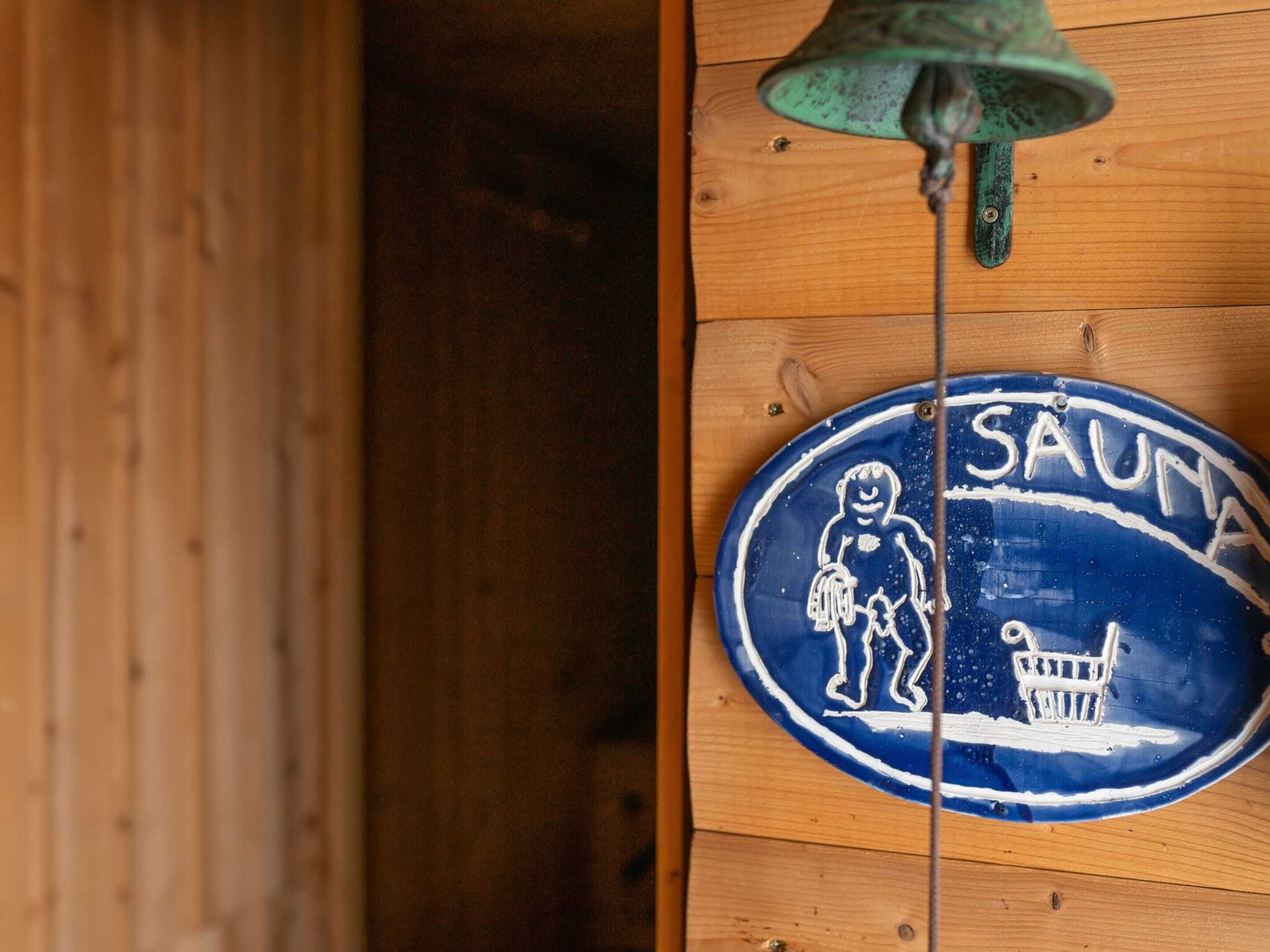 A blue and white sign with the word "SAUMA" and a figure holding a child.