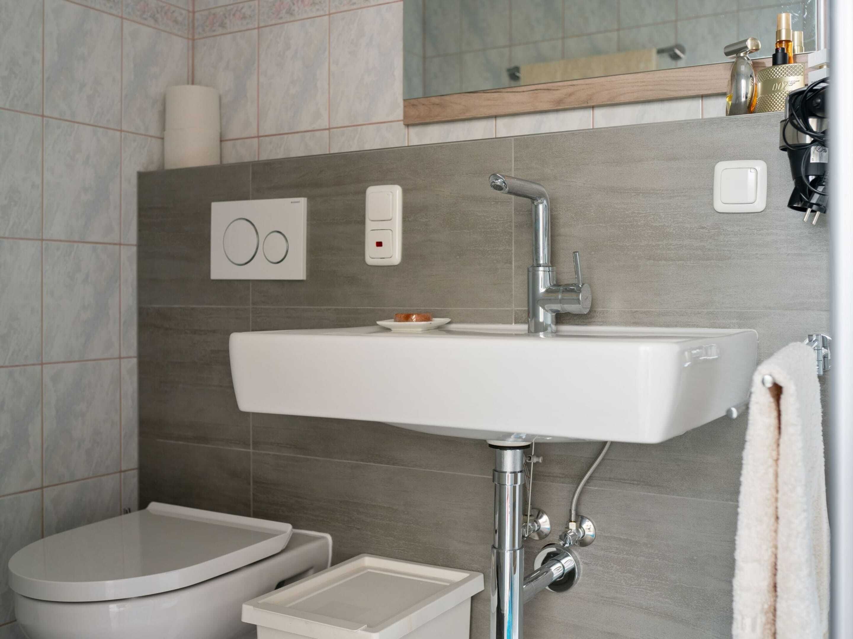 Een moderne badkamer met een wit wastafelmeubel, toilet en een bidet.