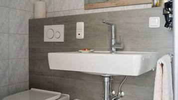 Een moderne badkamer met een wit wastafelmeubel, toilet en een bidet.