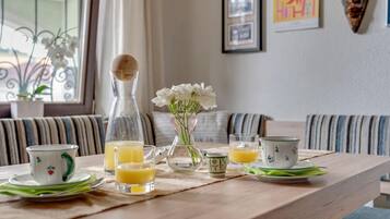 Ett frukostbord med en kanna, en tekanna, koppar och en vas med blommor.
