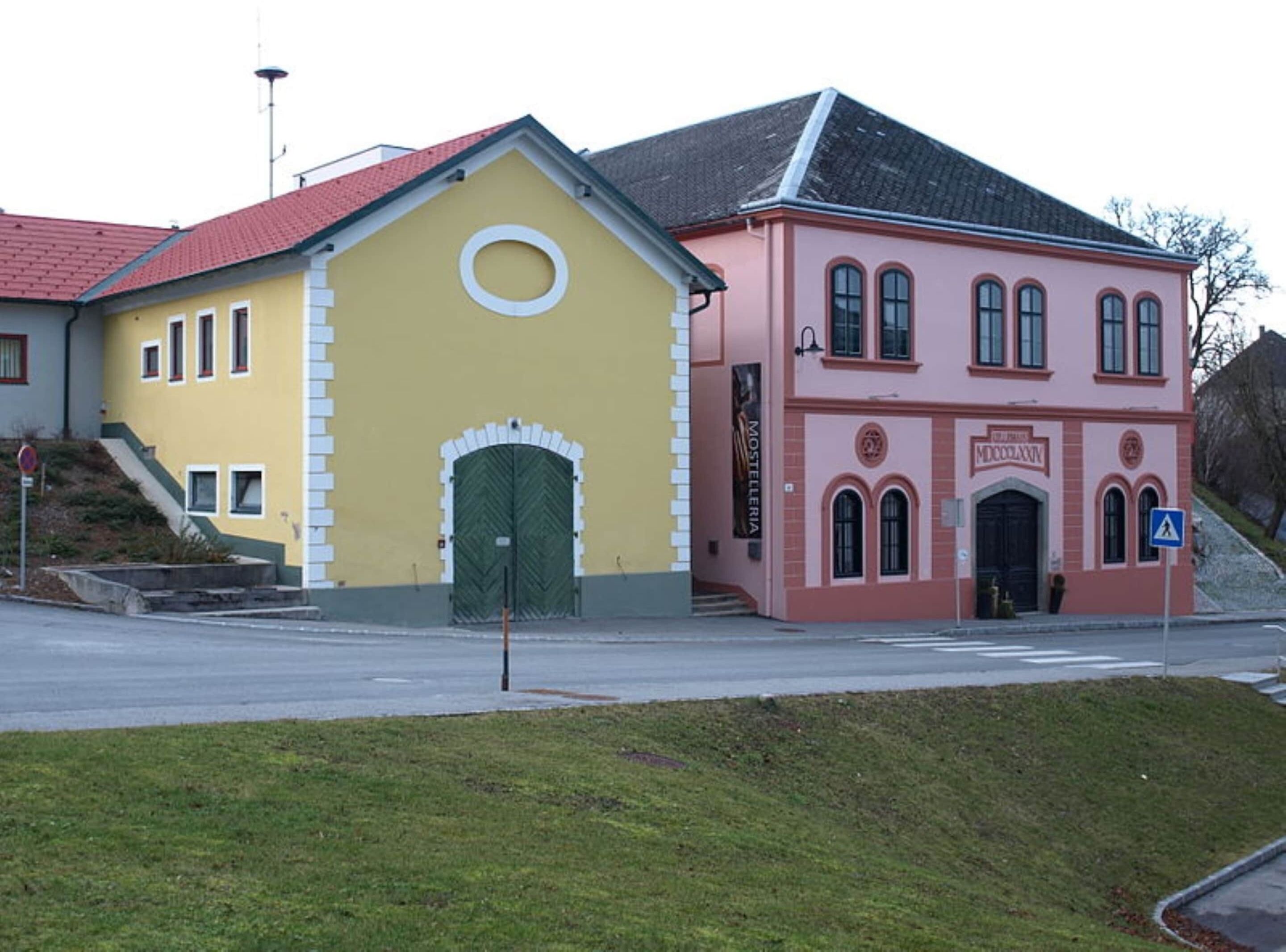 Een geel gebouw met een groene deur en een roze gebouw met gebogen ramen.