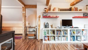 A living room with wooden floors, a fireplace, a TV, and a bookshelf filled with books. - Alpine Family Retreat in Bad Mitterndorf (Bad Mitterndorf)