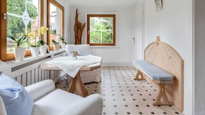 A cozy room with a white sofa, a wooden bench, a table with a vase, and a window with plants. - Alpine Family Retreat in Bad Mitterndorf (Bad Mitterndorf)
