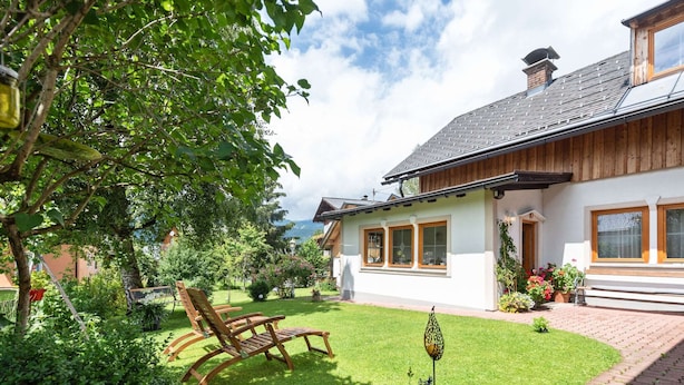 A house with a well-maintained garden, wooden deck, and a clear view of the mountains in the background. - Alpine Family Retreat in Bad Mitterndorf (Bad Mitterndorf)