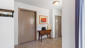Ein Flur mit zwei Türen, einem Holzschrank mit einer Vase und einem Gemälde an der Wand.
