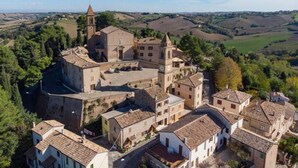 An aerial view of a historic town with a prominent church featuring a bell tower, surrounded by traditional buildings and rolling hills in the background. - Belvilla by OYO Le Castorelle (Colli al Metauro)