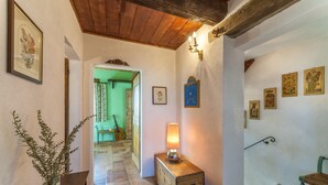 A hallway with a wooden bench, a vase with dried plants, a lamp on a wooden box, and framed pictures on the walls. - Belvilla by OYO Le Castorelle (Colli al Metauro)